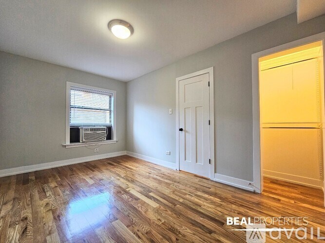 A room with wooden flooring and a window with blinds.