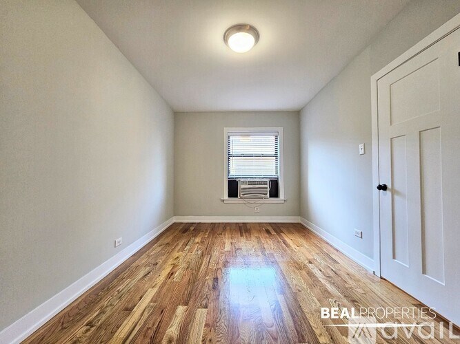 A room with wooden flooring and a window with blinds.