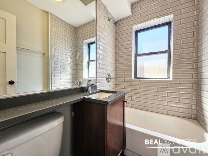 A bathroom with a tub, sink, and mirror.