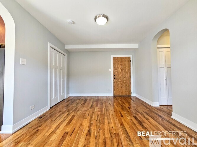 A room with wooden floors and white walls, with a door on the right side.