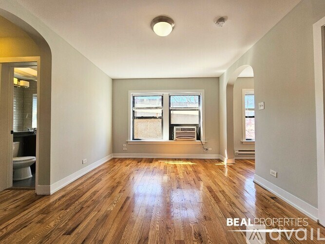 A spacious room with wooden floors and a large window.