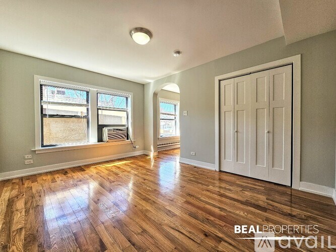 A spacious room with wooden floors and a large window.