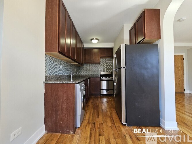 A kitchen with a black fridge and wooden cabinets.