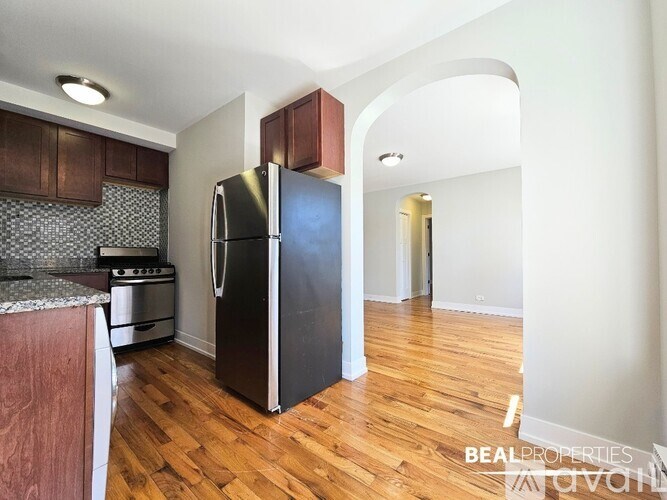 A kitchen with a black fridge and wooden floors.