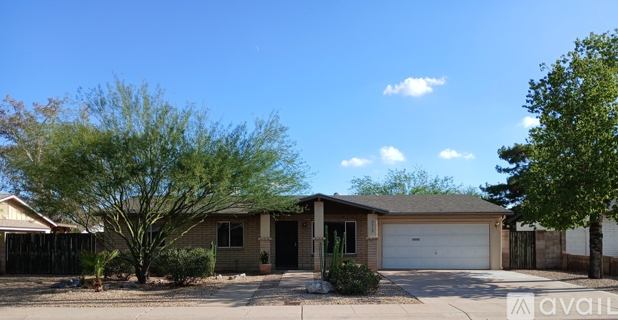 A house with a garage and a tree in front.