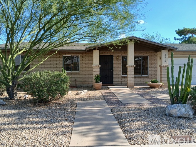 A house with a gravel driveway and a cactus in front.