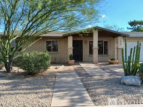 A house with a gravel driveway and a cactus in front.