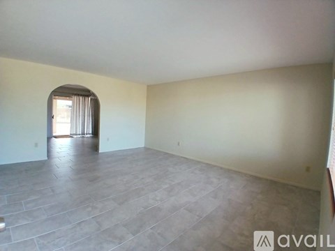 A spacious room with a grey floor and a window with curtains.