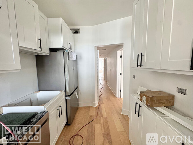 A kitchen with white cabinets and a refrigerator.