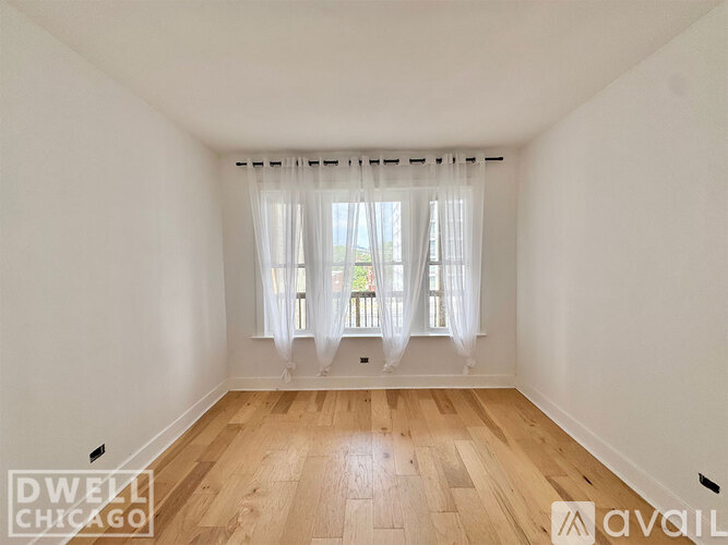 A room with a window covered by white curtains.