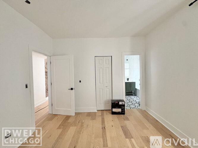 A room with white walls and wooden flooring, with a box on the floor.