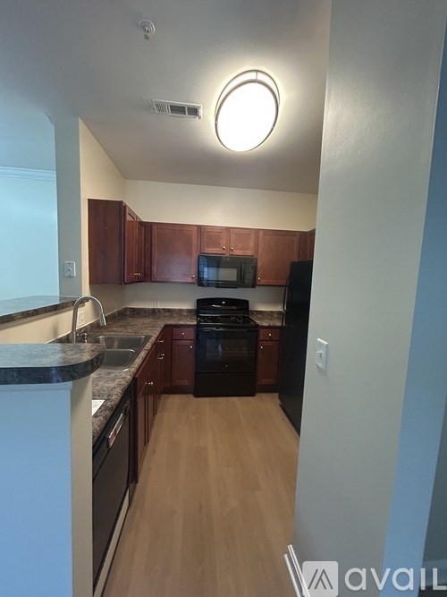 A kitchen with brown cabinets and a black refrigerator.