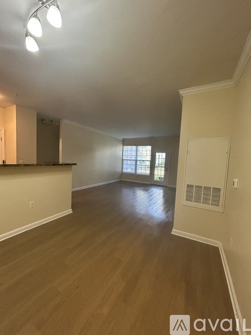 A spacious room with wooden flooring and a window.