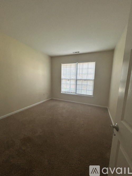 A room with a carpeted floor and a window with blinds.
