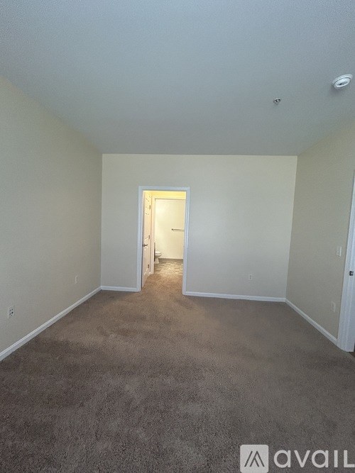 A carpeted room with a doorway leading to another room.