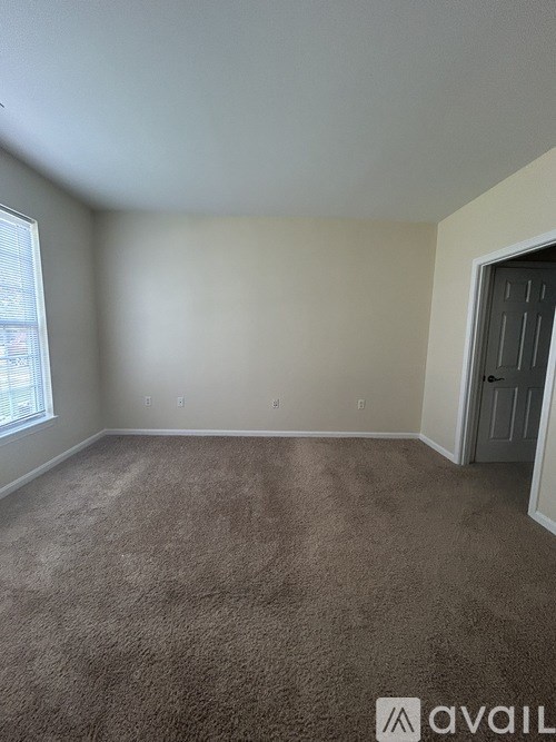 A room with a carpeted floor and a door on the right side.