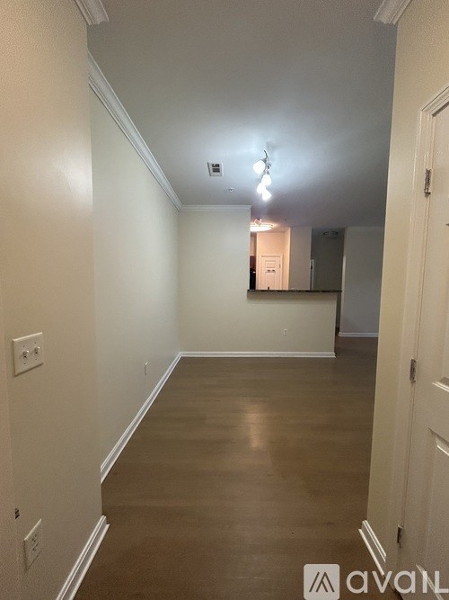 A long hallway with white walls and wood flooring.