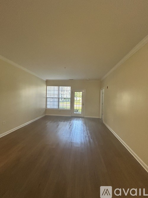 A room with wooden floors and a window with blinds.