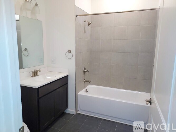A bathroom with a white tub and a sink with a mirror.