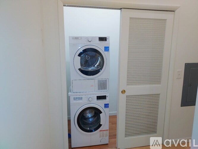 A white front loading washing machine with a dryer on top is in a room.