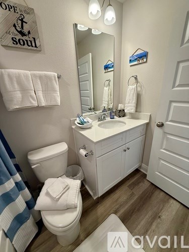 A bathroom with a toilet, sink, mirror, and a sign on the wall.