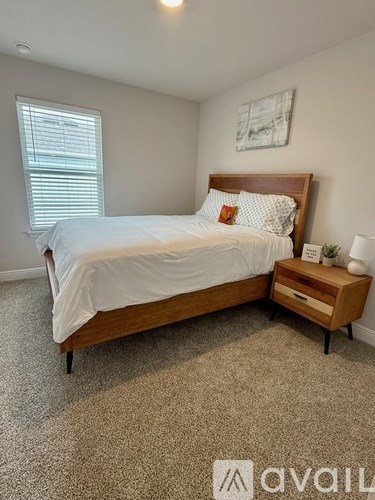 A bedroom with a bed, nightstand, and window.