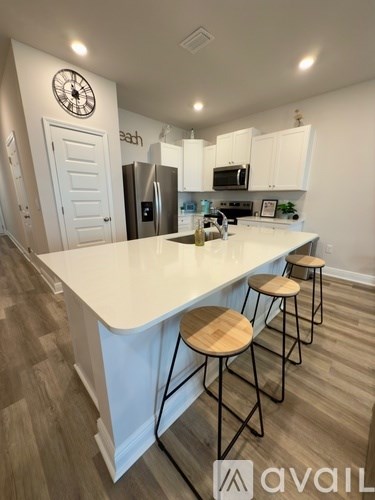 A kitchen with a white countertop and wooden stools.