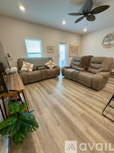 A living room with a tan couch and a wooden floor.
