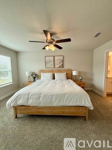 A bedroom with a large bed and a ceiling fan.