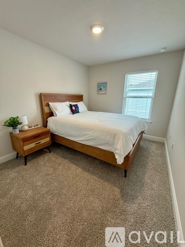 A bedroom with a bed, nightstand, and window.