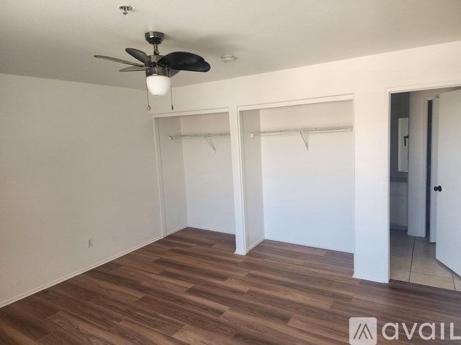 Empty room with a ceiling fan and wooden flooring.