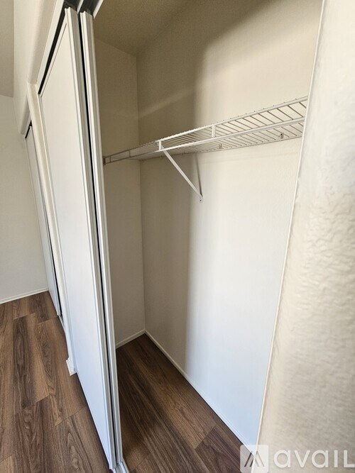 A white refrigerator with a shelf is in a room with wood flooring.