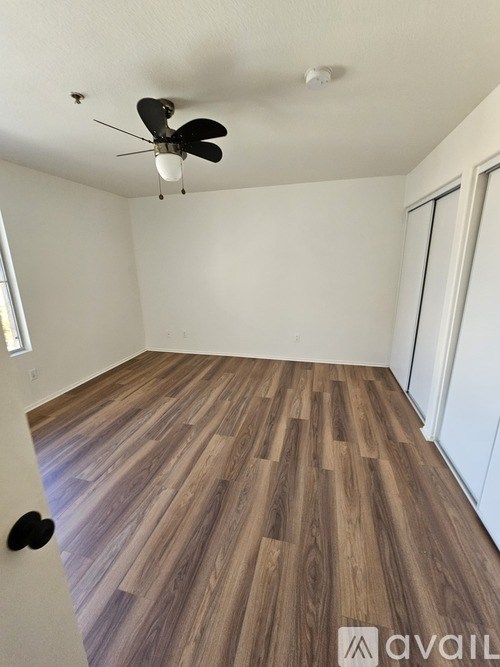 A room with wooden flooring and a ceiling fan.