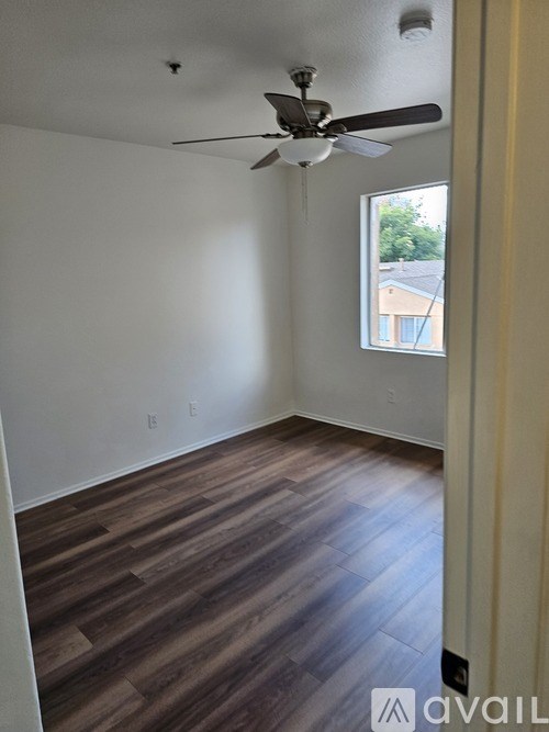 A room with a ceiling fan and wooden flooring.