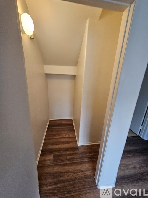 A hallway with wood flooring and white walls.