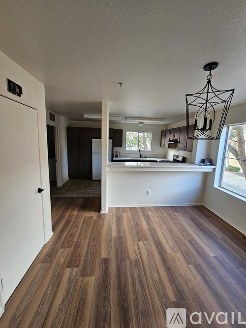 A room with wooden floors and a white door leading to another room.
