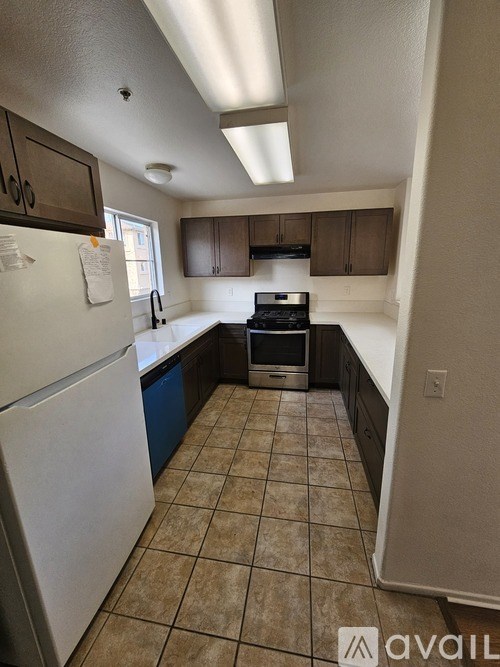 A kitchen with a white refrigerator and brown cabinets.