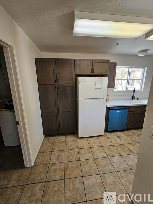 A kitchen with brown cabinets and a white fridge.