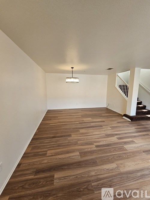 A room with wooden flooring and a staircase on the right side.
