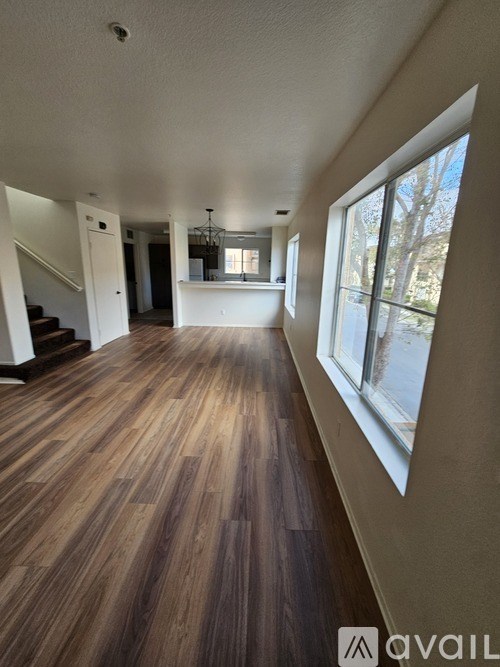 A long hallway with wood floors and a staircase.
