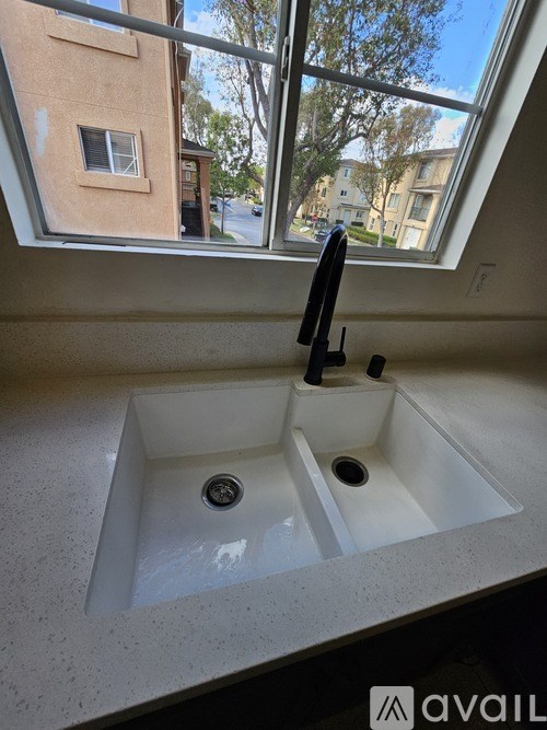 A white sink in a bathroom with a window above it.
