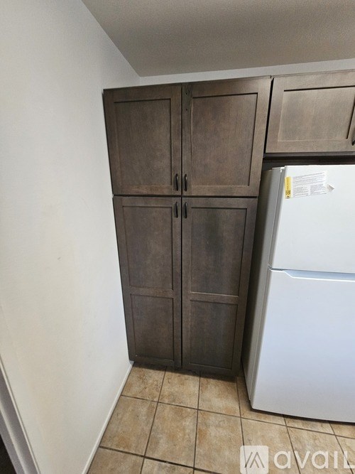 A kitchen with a white fridge and a brown cabinet.