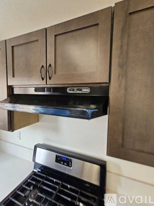 A stove top oven with a digital display is installed under a cabinet.