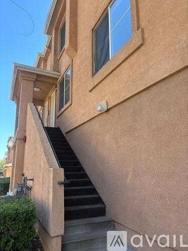 A staircase leads up to a window on a tan building.