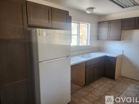 A kitchen with a white refrigerator and brown cabinets.