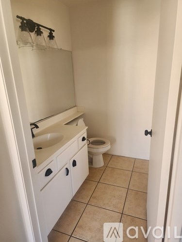A white bathroom with a toilet, sink, and cabinet.