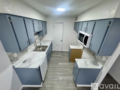 A kitchen with blue cabinets and a marble countertop.