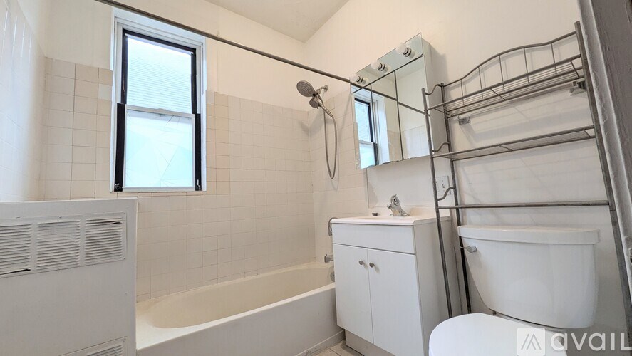 A white bathroom with a tub, sink, and mirror.