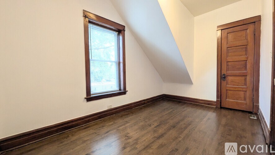 A room with a wooden floor, a window, and a door.