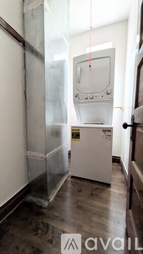 A white fridge in a room with wooden floors.